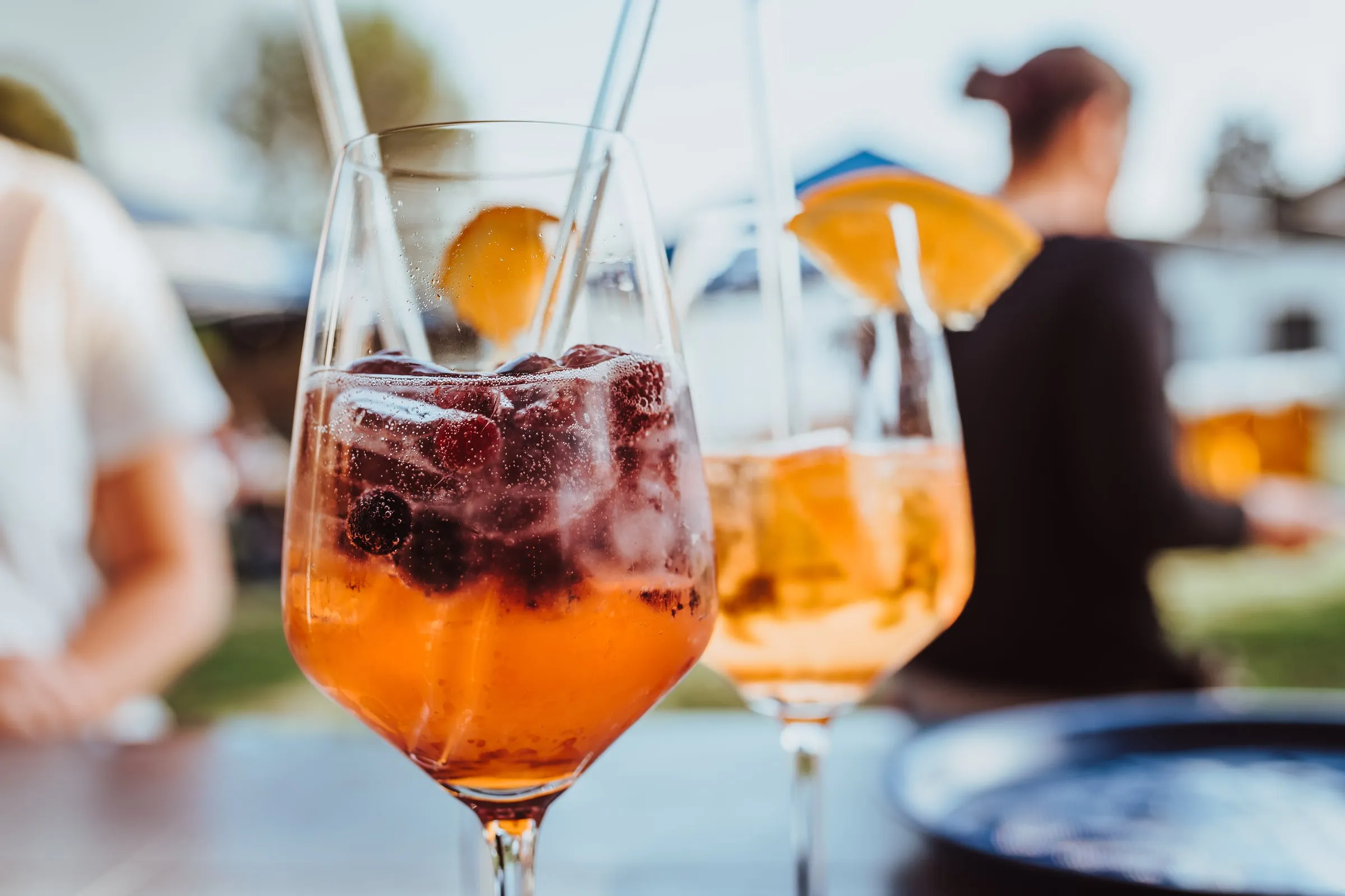 Zwei Aperitif-Gläser mit Beeren und Orange auf einem Tisch im Biergarten