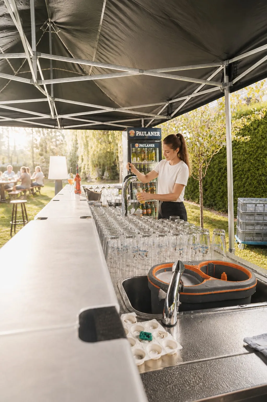 Servicepersonal des Borchener Biergartens zapft an einer aufgebauten Theke unter einem Pavillon